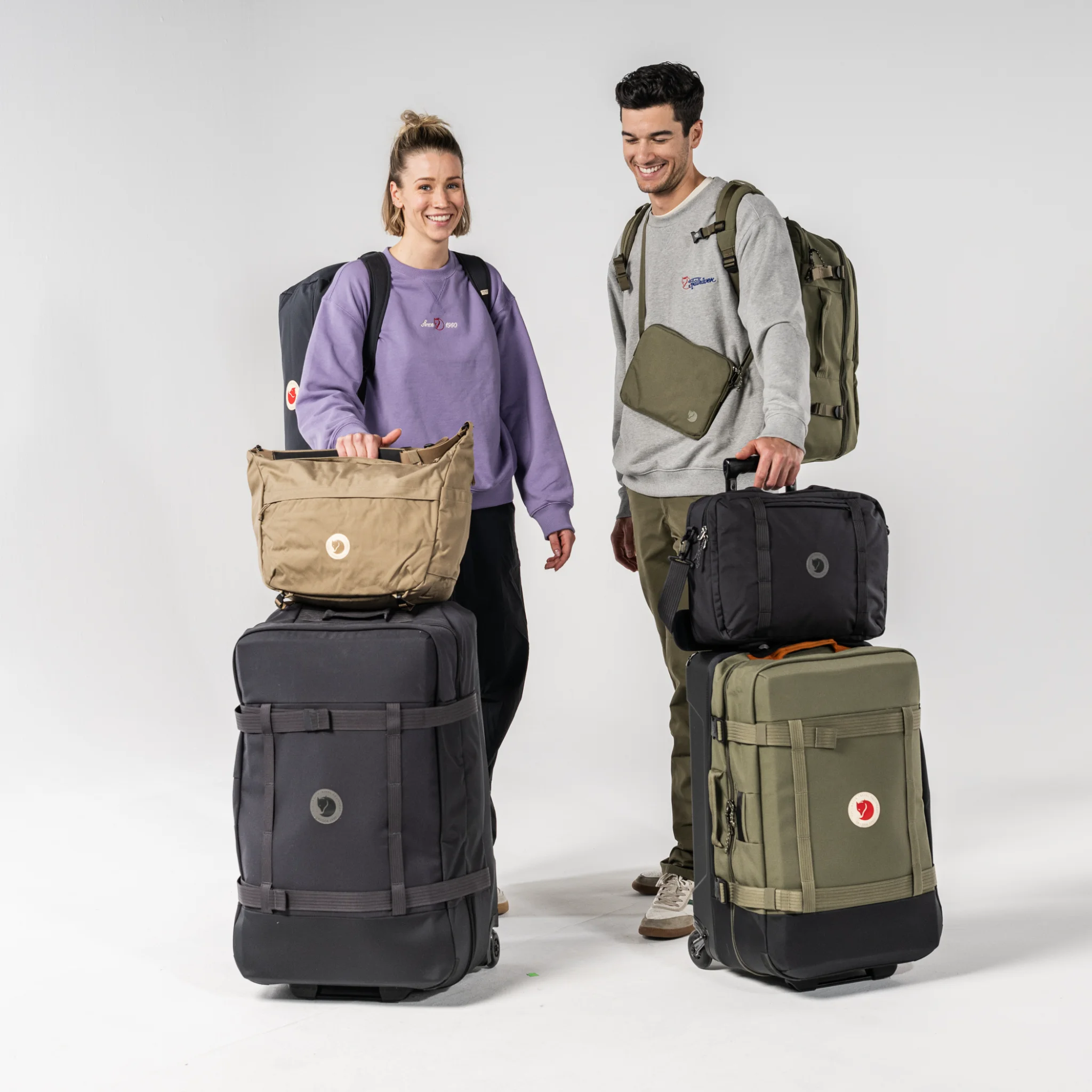 Fjällräven Taschenkollektion: Reiserucksack, Duffel und Roller in gedeckten Farben auf hellem Holztisch