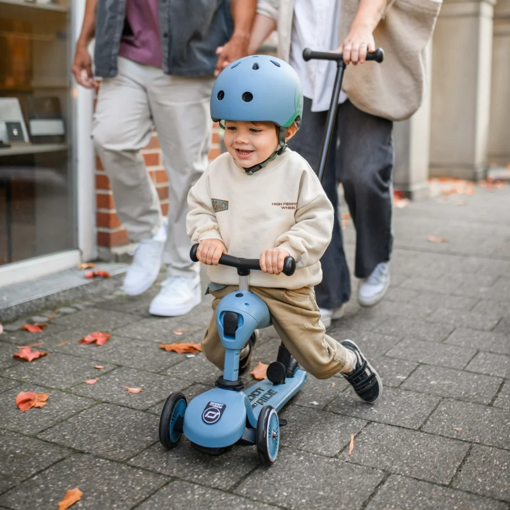 Toddler in a helmet riding a blue Scoot and Ride Highwaykick 1 on a pavement