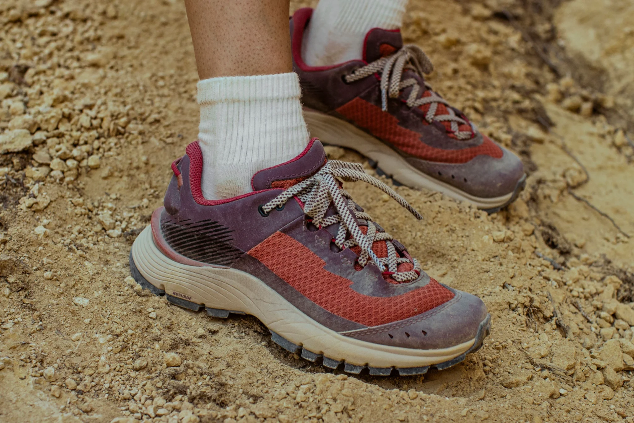 Rode trailschoenen op een zanderig pad
