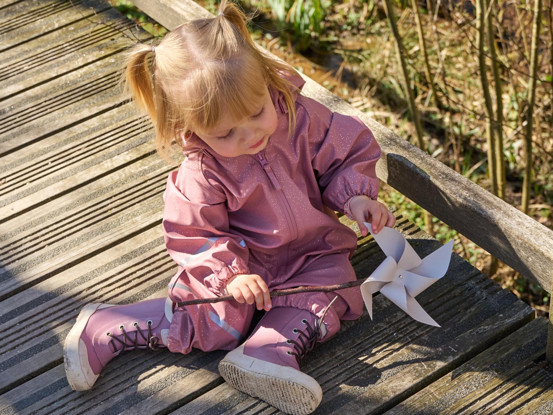 CeLaVi rain set flat lay: red PU rain jacket, rain trousers, natural rubber wellies and merino mittens