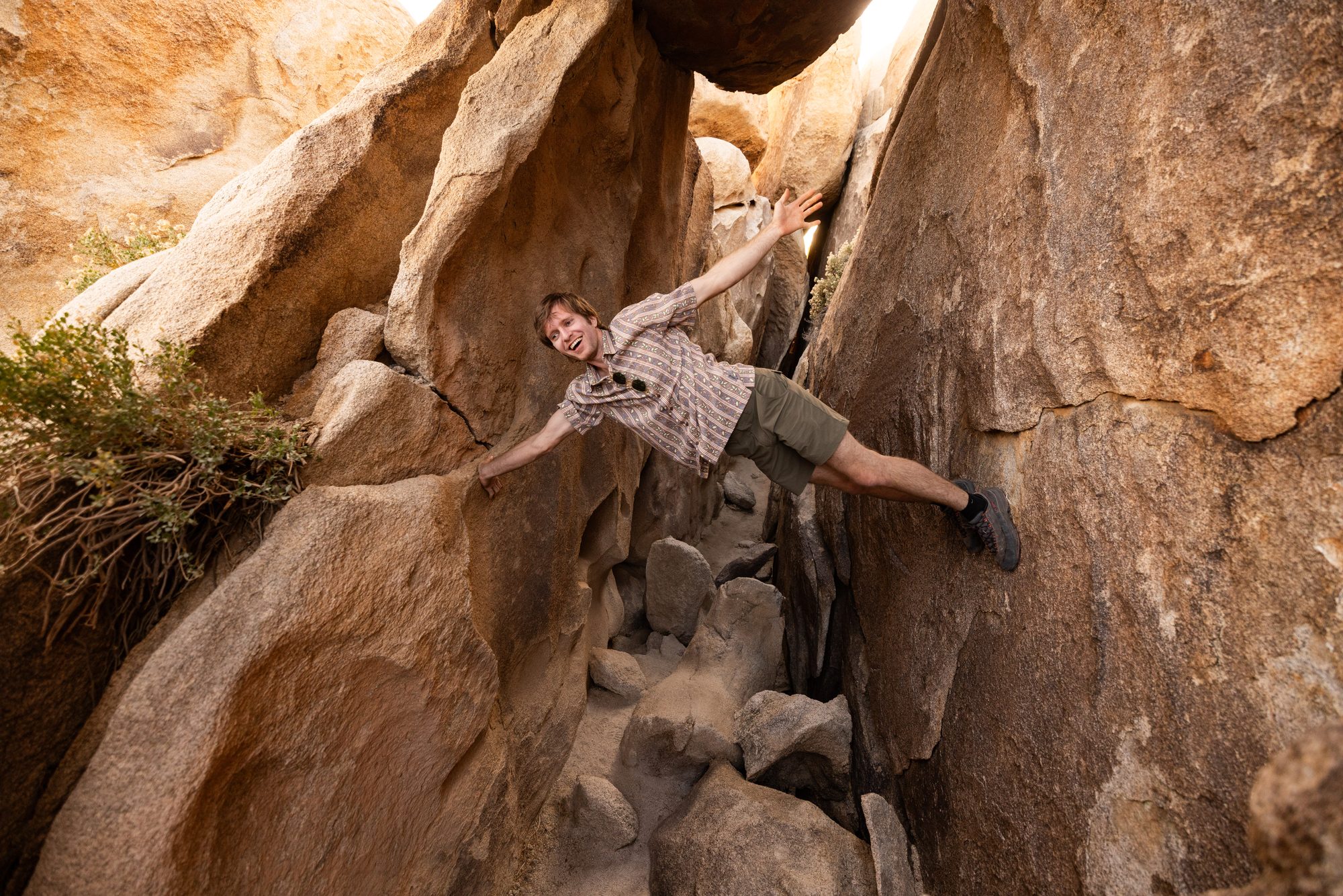 Man scrambling playfully between large boulders in Royal Robbins clothing