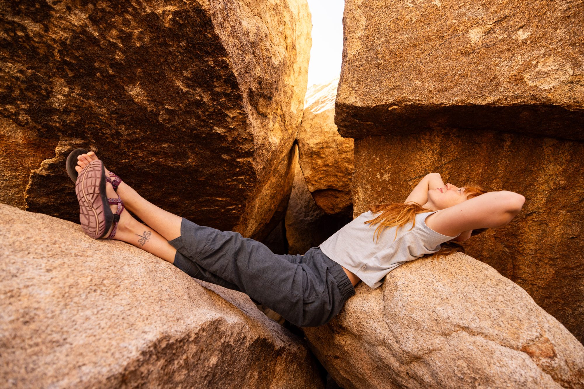 Woman relaxing on rocks in a desert landscape in Royal Robbins outdoor clothing